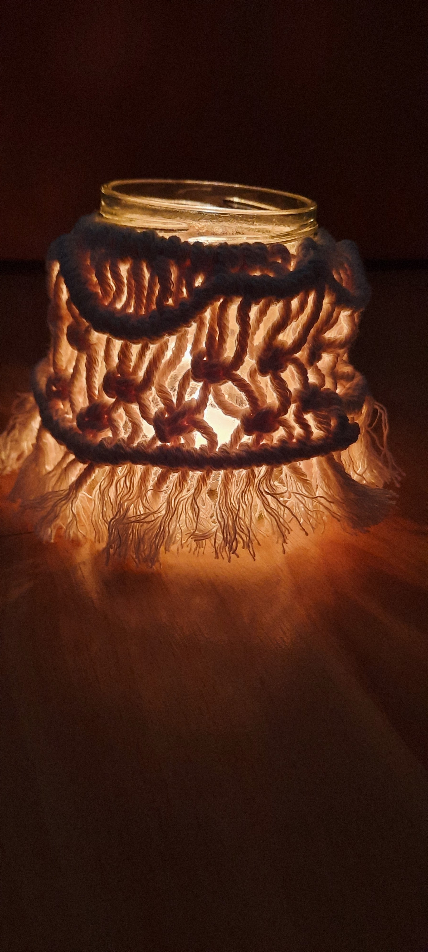 Decorative glass lantern with woven top on a dark background