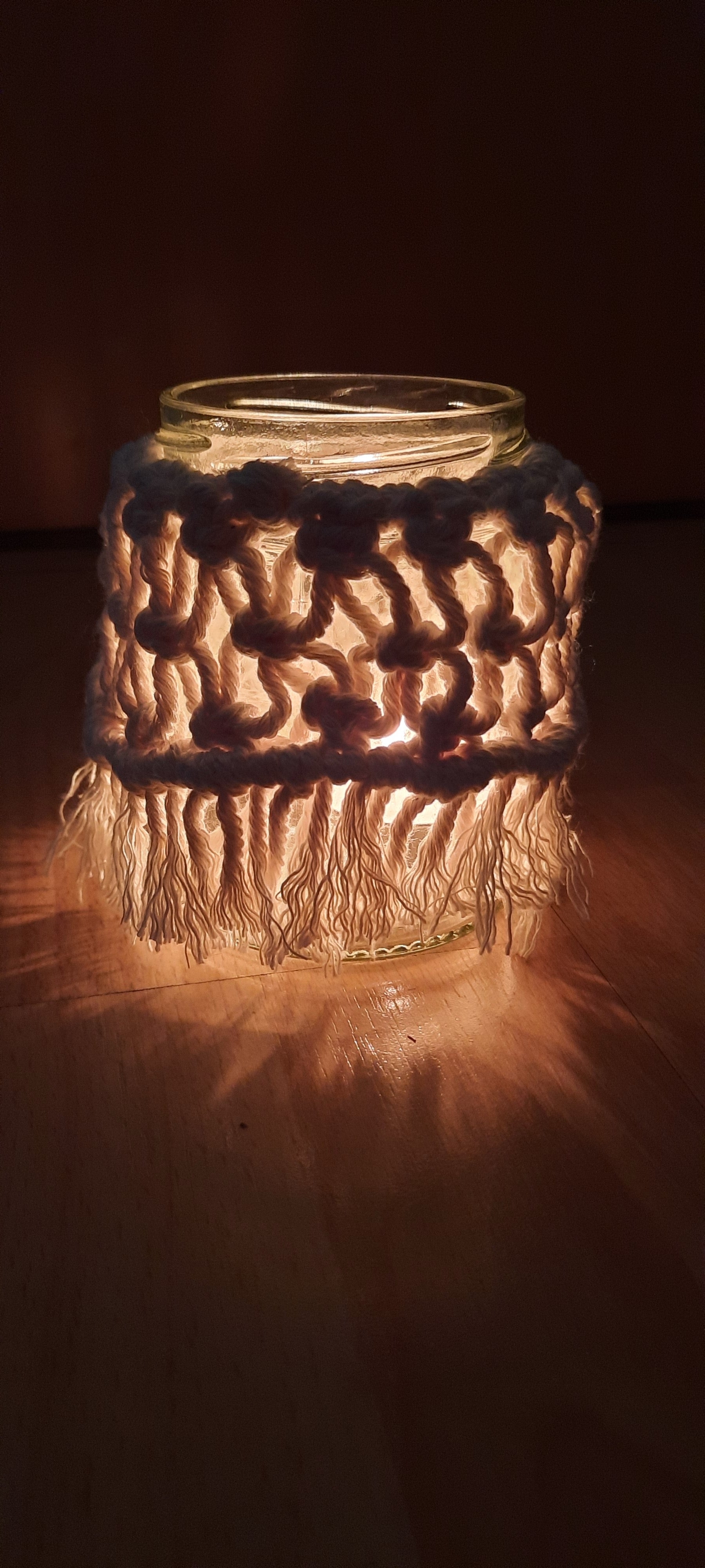Glass jar with a crocheted brown cover on a dark background