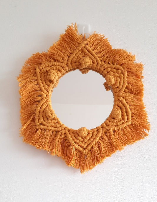 Orange macrame wall hanging on a white background