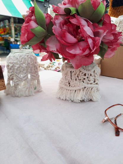 Floral arrangement in a macrame holder on a table with a blurred background