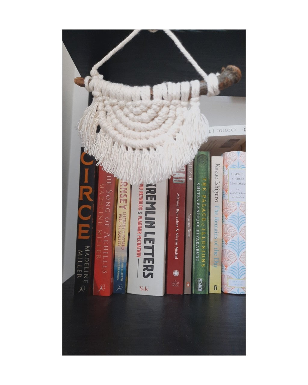 Macrame wall hanging on a bookshelf with books below