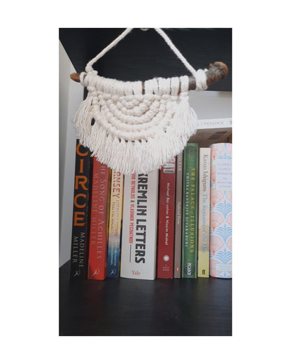 Macrame wall hanging on a bookshelf with books below