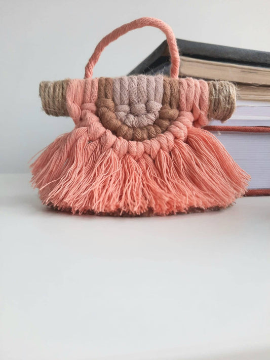 Pink macrame mini hanging with tassels and accents on a white surface