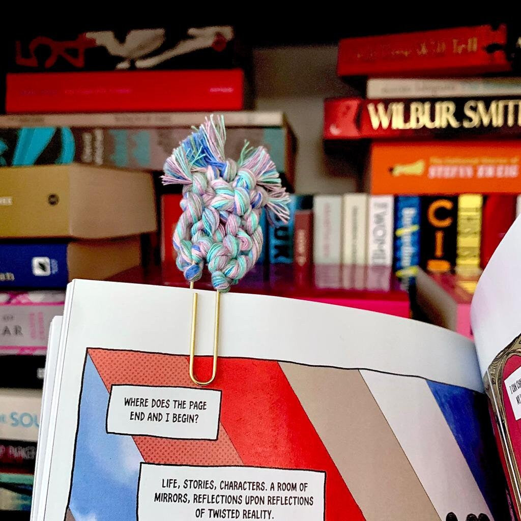 Colorful knotted paper clip on a comic book with books in the background
