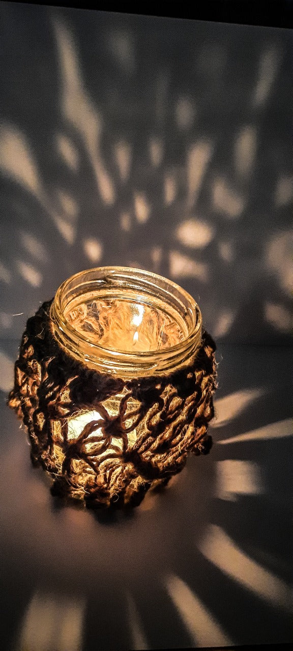 Decorative candle holder with a lit candle casting shadows on a dark background