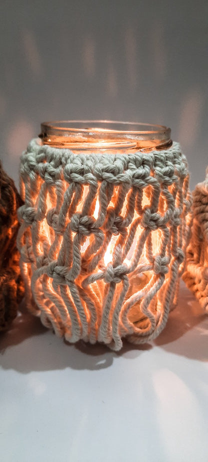 Glass candle holder with a textured crochet cover on a white background